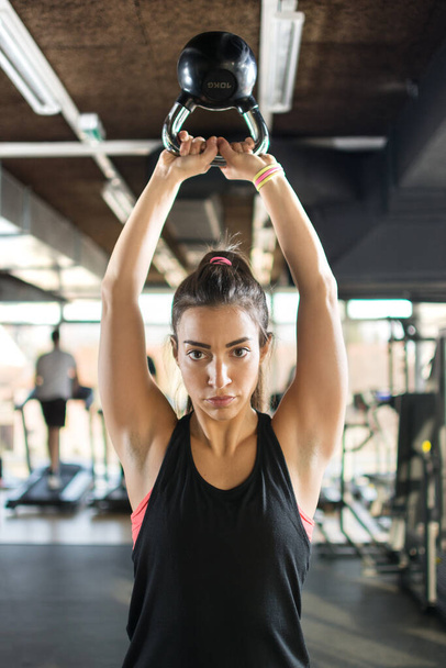 Menina desportiva atraente fazendo exercícios com kettlebell em um ginásio - Foto, Imagem