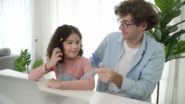 Smart daughter put pencil on ear and showing thumb while caucasian dad explain writing engineering prompt or generated AI by using laptop on table. Caucasian father playing with schoolgirl. Pedagogy. - Video, Çekim