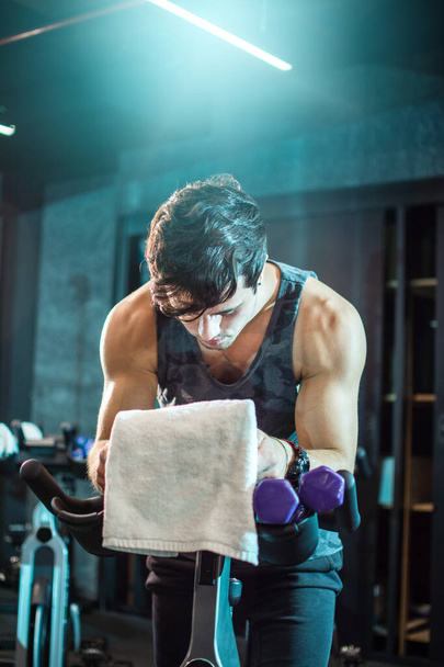 Sporty man exercising on a stationary bike at gym - Photo, Image