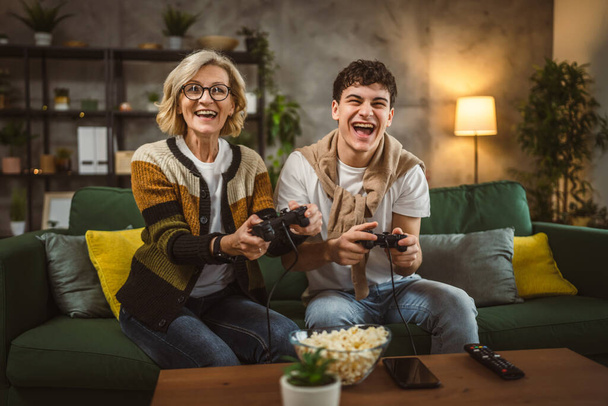 teenager male and his mother mature woman man play console video game - Photo, Image