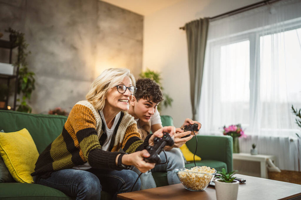 teenager muž a jeho matka zralé žena muž hrát konzole videohry - Fotografie, Obrázek