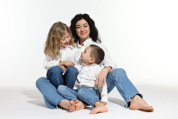 Little children with their mother sitting together on white background - Foto, immagini