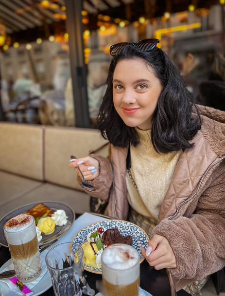 Giovane bella donna bruna che mangia gelato al caffè di strada a Parigi, Francia. Ritratto stile di vita esterno  - Foto, immagini