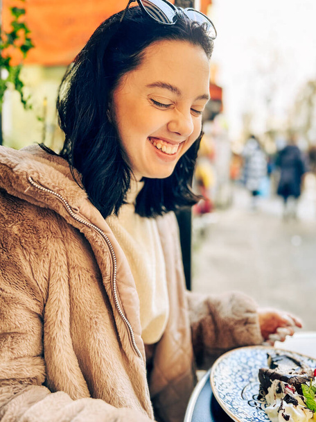 Jovem morena bonita comendo sorvete no café da rua em Paris, França. Retrato de estilo de vida ao ar livre  - Foto, Imagem