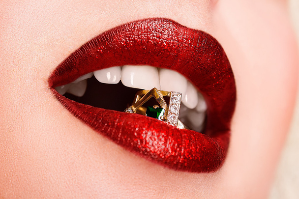 Close-up of beautiful woman's lips with bright fashion dark red glossy makeup. Macro lipgloss cherry make-up. Mouth with wedding gold diamond ring - Photo, image