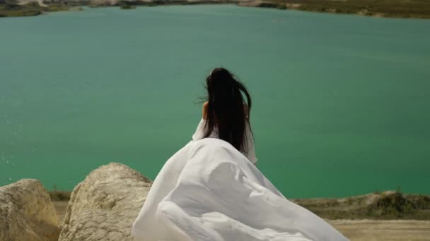 Nevěsta se dívá na tyrkysovou vodu a její bílé šaty za ní vlály. - Záběry, video