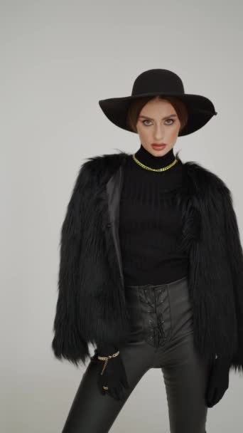 Striking a pose that radiates confidence, the model is clad in a chic black ensemble with a statement hat and textured coat. - Footage, Video