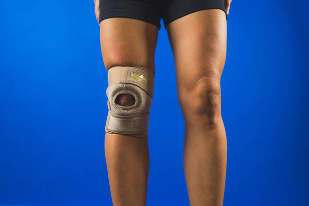 vrouw draagt een beschermende beugel op haar knie, gezondheidszorg concept. Hoge kwaliteit foto - Foto, afbeelding