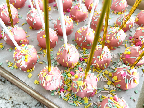 Disponibili ordinatamente su pergamena, questi pop di torta rosa immersi a mano sono una delizia giocosa, ornata da un arcobaleno di spruzzi che aggiungono un tocco festivo alle dolci delizie.. - Foto, immagini