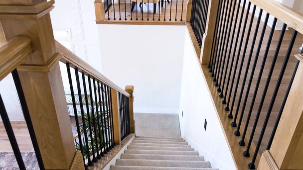 A imagem capta o detalhe de uma escadaria moderna bem projetada, forrada com tapete bege de pelúcia, complementada por paredes brancas e balaústres de madeira.. - Foto, Imagem