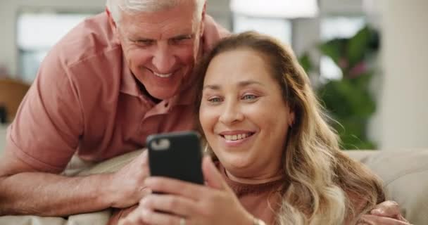 Αρχική σελίδα, χαλαρώστε και ηλικιωμένο ζευγάρι με smartphone, δακτυλογράφηση και σύνδεση με τη βοήθεια και τα μέσα κοινωνικής δικτύωσης σε ένα σαλόνι. Διαμέρισμα, ανώτερος άνθρωπος ή ώριμη γυναίκα με κινητό τηλέφωνο ή internet με ψηφιακή εφαρμογή ή διδασκαλία. - Πλάνα, βίντεο