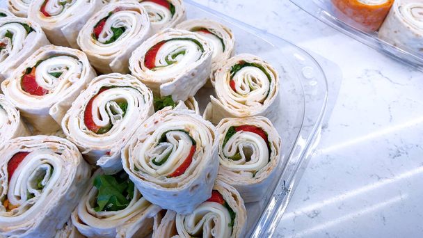 Podlewający usta wyświetlacz kanapki pinwheel wypełnione świeżych zieleni i mięs delikatesów, idealny na każde spotkanie lub szybki lunch. - Zdjęcie, obraz