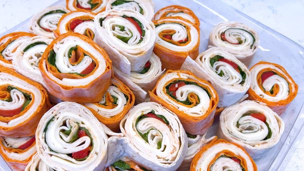Un étalage alléchant de sandwichs aux pinwheel remplis de légumes frais et de charcuteries, parfait pour tout rassemblement ou déjeuner rapide. - Photo, image