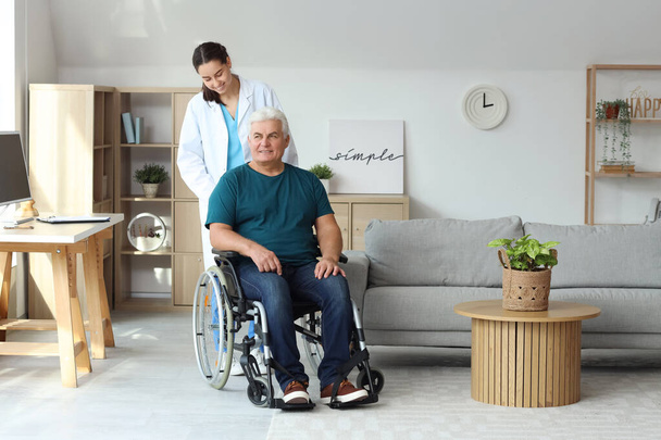 Homme âgé en fauteuil roulant avec infirmière à la maison - Photo, image