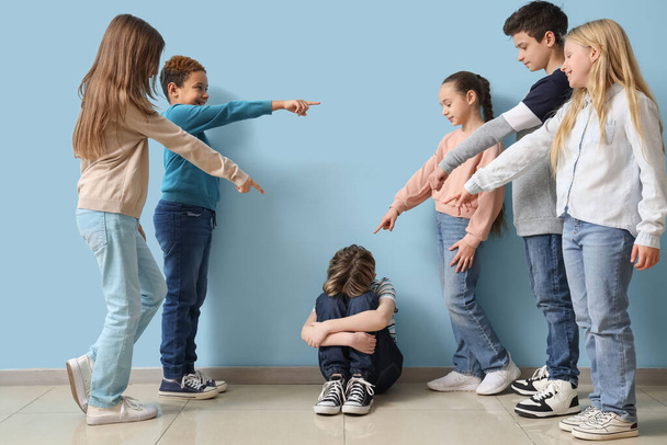 Schüler schikanieren kleinen Jungen nahe blauer Wand - Foto, Bild