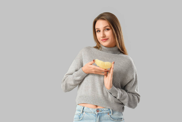 Young woman with pomelo slice on light background - Photo, Image
