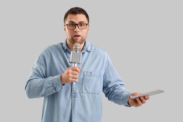 Periodista masculino con micrófono y tableta sobre fondo claro - Foto, imagen