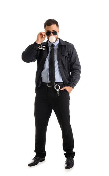 Офицер полиции выдувает жвачку на белом фоне - Фото, изображение