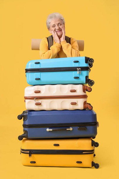 Senior Touristin mit Koffern auf gelbem Hintergrund - Foto, Bild