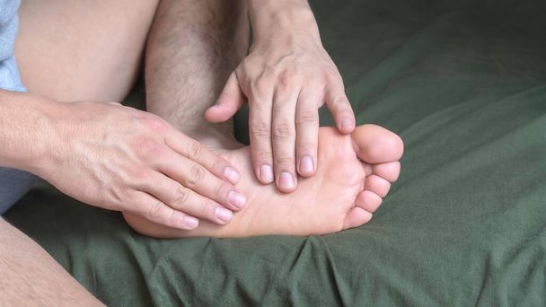 Ayak tabanının kemerine elleriyle masaj yapan bir adam. - Fotoğraf, Görsel