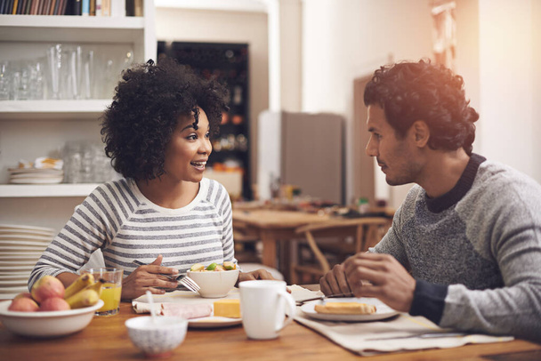 Frühstück, glücklich und Paar im Gespräch in der Küche Zusammenhalt in der Wohnung. Lächeln, Liebe und Mann und Frau reden und essen gesundes Essen oder morgens am Esstisch im modernen Zuhause - Foto, Bild