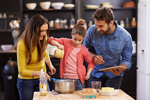 Οικογένεια, κουζίνα και tablet για το ψήσιμο με προσοχή, συνταγή online με υλικά για κέικ ή επιδόρπιο με υποστήριξη και χειροποίητα. Η μαμά, ο μπαμπάς και το παιδί μαγειρεύουν μαζί με αγάπη για το δέσιμο ή τη διδασκαλία. - Φωτογραφία, εικόνα