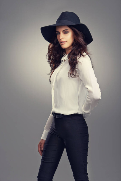 Mode, modèle et portrait de femme en studio avec chapeau chic, tendance et élégant pour la tenue. Confiant, la fierté et la jeune femme avec un style élégant et accessoire isolé par fond gris - Photo, image
