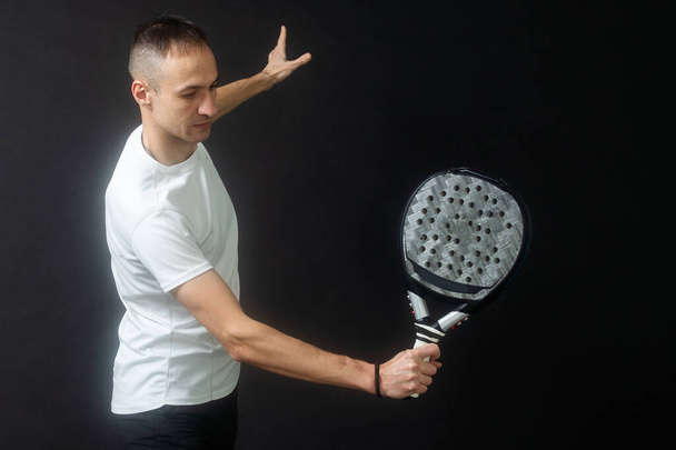 Padel-Tennisspieler mit Schläger in der Hand. Paddeltennis, auf schwarzem Hintergrund. Hochwertiges Foto - Foto, Bild