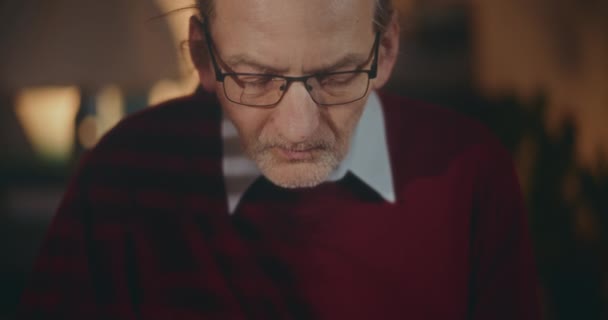 Huomaavainen iäkäs mies hämärässä kotona, heijastaen juhlallisesti elämänmatkaa yön hiljaisuudessa - Materiaali, video