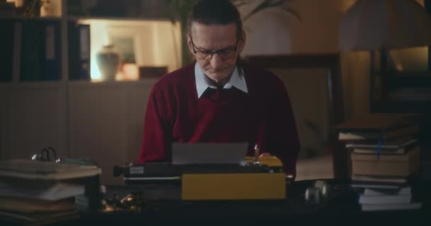 Starszy pan, piszący na maszynie do pisania, przewrotnie piszący książkę w ciszy swego domu, głęboko w kontemplacji pod nocnym niebem - Materiał filmowy, wideo