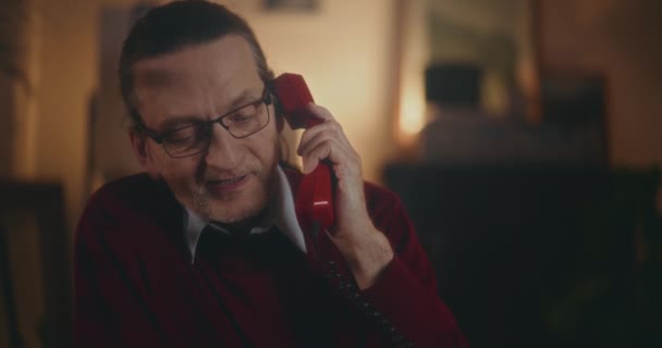 Oudere heer gaat in nostalgische gesprek op een vintage telefoon onder de rustige sfeer van de nacht - Video