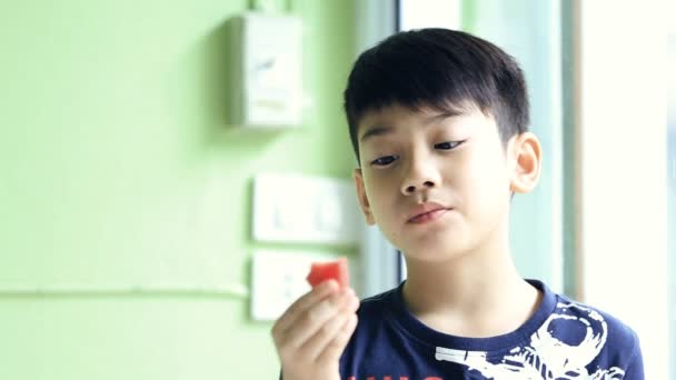 Mały azjatycki chłopiec ładny zjada dojrzały arbuz - Materiał filmowy, wideo