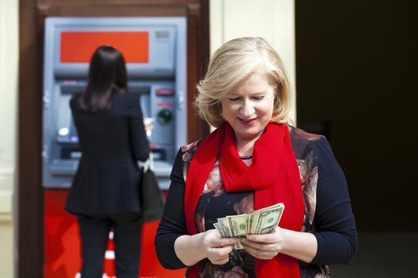 Zralá blonďatá žena počítání peněz poblíž Atm - Fotografie, Obrázek