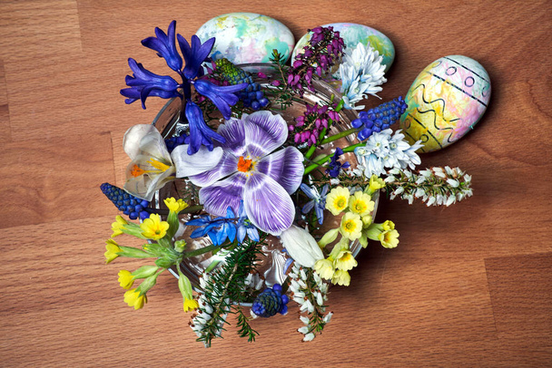 een boeket bloeiende lentebloemen en paaseieren op een houten tafel, Polen - Foto, afbeelding