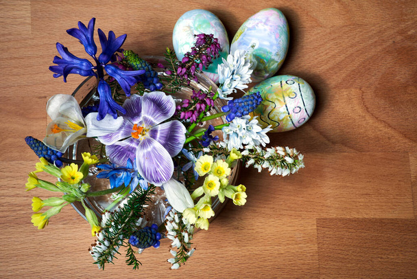 букет цветущих весенних цветов и пасхальных яиц на деревянном столе, Польша - Фото, изображение