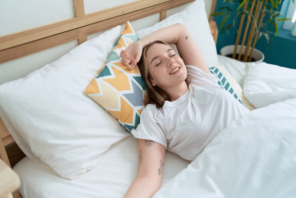 Giovane donna caucasica sdraiata sul letto dormire in camera da letto - Foto, immagini