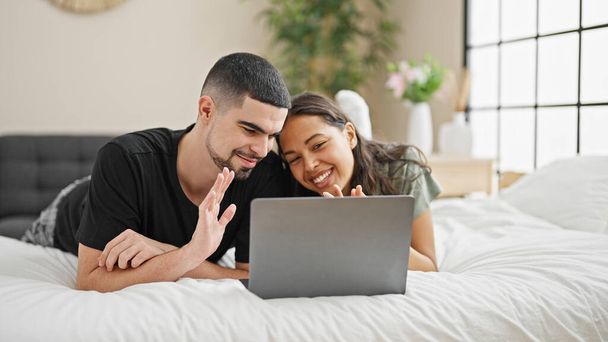 Adorable couple souriant et relaxant à la maison, couché au lit bavarder et profiter d'un appel vidéo charmant dans leur chambre confortable et magnifiquement conçu. - Photo, image