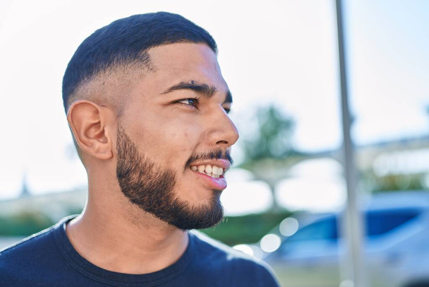 Mladý latinský muž se usmívá sebevědomě dívá stranou na ulici - Fotografie, Obrázek
