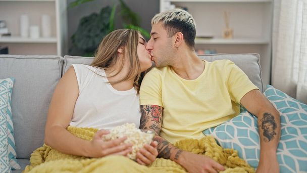 Beautiful couple eating popcorn kissing at home - Photo, Image