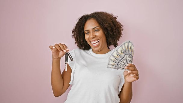 African american woman with keys and money on pink background - 写真・画像
