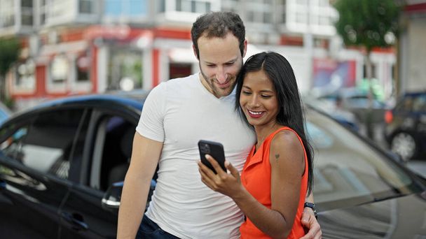 Hermosa pareja usando smartphone de pie en coche en la calle - Foto, Imagen