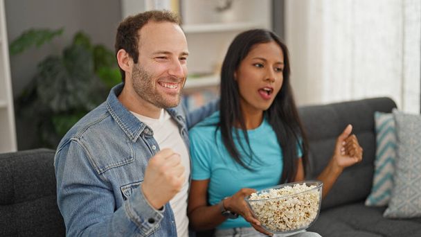 自宅で祝うポップコーンを食べているテレビを見ている美しいカップル - 写真・画像