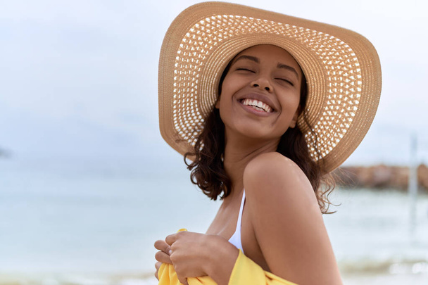 Young african american woman smiling confident wearing summer hat and bikini at beach - Fotoğraf, Görsel