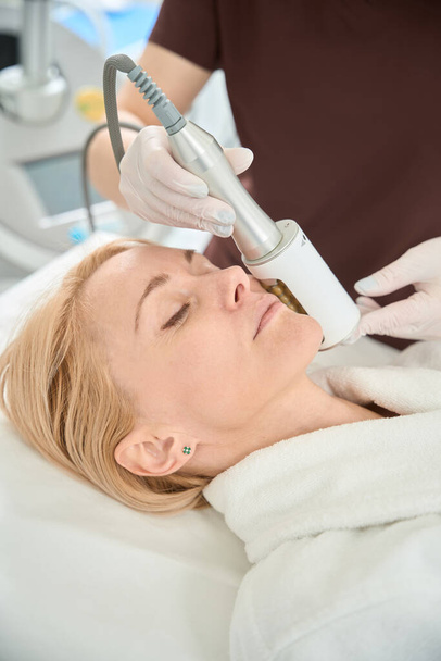 Çekici bir kadın tıbbi kanepede gözleri kapalı yatıyor, endosfer tedavisine katılıyor, lenf ve venöz tıkanıklığın tedavisine katılıyor, metabolik işlemler etkinleşiyor. - Fotoğraf, Görsel