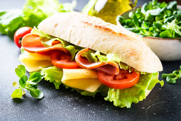 Szendvics salátával, sajttal, paradicsommal és sonkával. Egészséges gyorskaja, reggeli vagy ebéd. Közelről.. - Fotó, kép