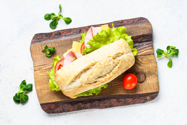 Ciabatta sendvič se salátem, sýrem, rajčaty a šunkou. Rychlé občerstvení, občerstvení nebo oběd. - Fotografie, Obrázek