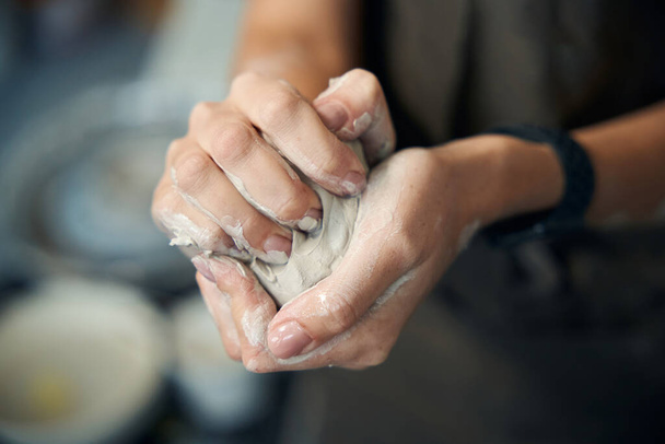 Unerkennbare Frau mit Ton bereitet Kunsthandwerker auf die Herstellung von Keramikprodukten im Kunstatelier vor - Foto, Bild