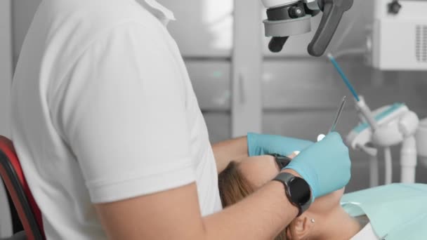 Κατά τη διάρκεια της περιοδοντικής χειρουργικής, ο οδοντίατρος χρησιμοποιεί ένα μικροσκόπιο για την ακριβή κοπή και θεραπεία των ιστών γύρω από τα δόντια. Ανίχνευση και θεραπεία τερηδόνας και άλλων παθολογικών διεργασιών. Υψηλής ποιότητας 4k - Πλάνα, βίντεο