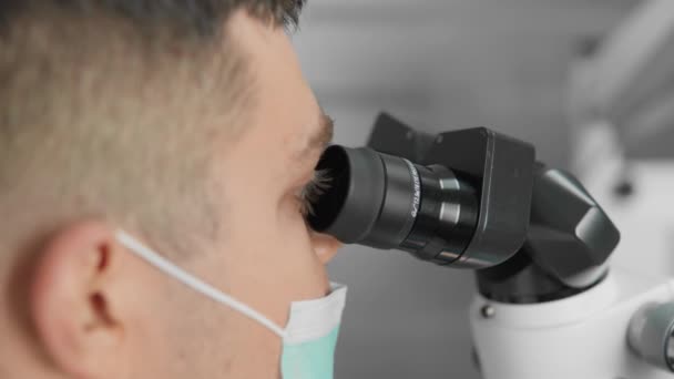 Hammaslääkäri käyttää hampaiden mikroskooppi suorittaa tarkkoja ja luotettavia hammaslääkärin menettelyjä, auttaa itseään mikroskoopilla, suorittaa tarkka käsittely ja sijoittaminen hammasimplantit. Laadukas 4k - Materiaali, video
