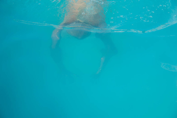 Mies ui veden alla uima-altaassa kesälomalla. Uimassa altaassa. Sininen. - Valokuva, kuva